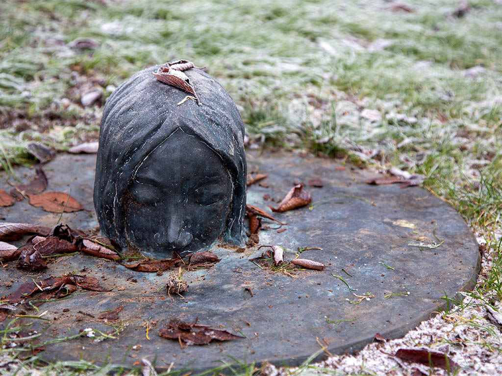 Skulptur med ett ansikte på brunnslock.