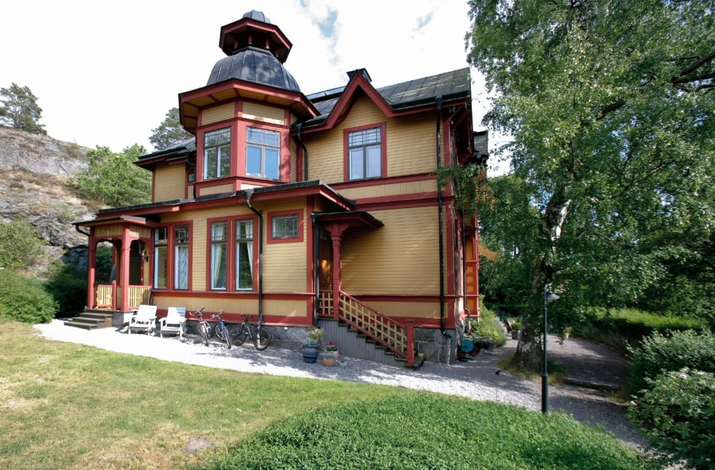 Färgfoto av huset i trä målat gult och rött.