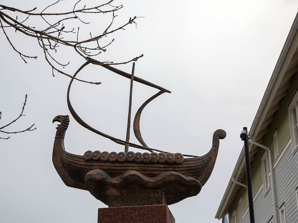 Vikingaskepp i brons mot en grå himmel.