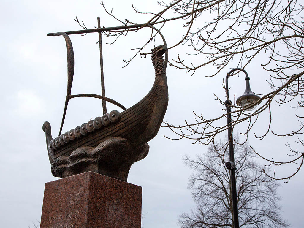Vikingaskepp i brons mot en grå himmel.