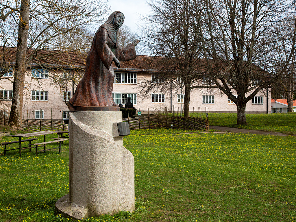 Skulptur av en kvinna i dok på en vit spiralformad sockel