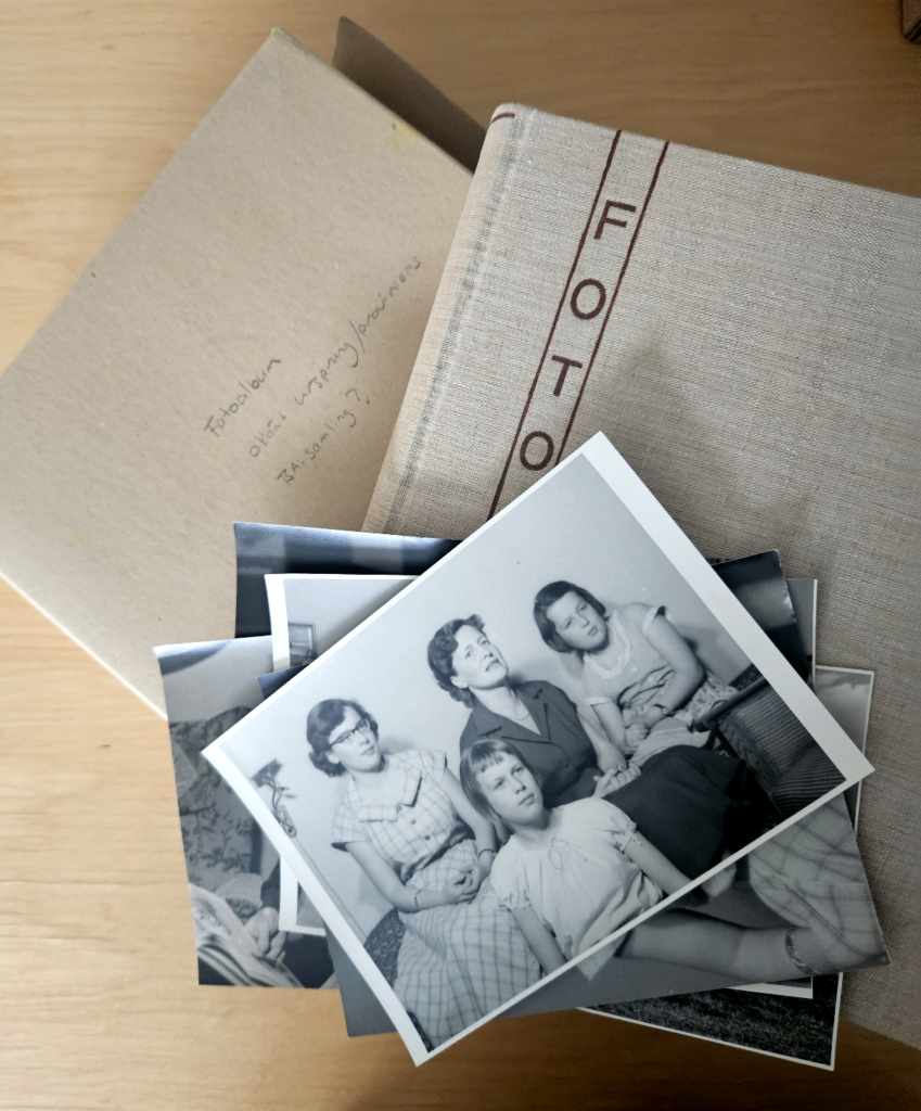 Svartvita fotografier på hög ovanpå ett fotoalbum.
