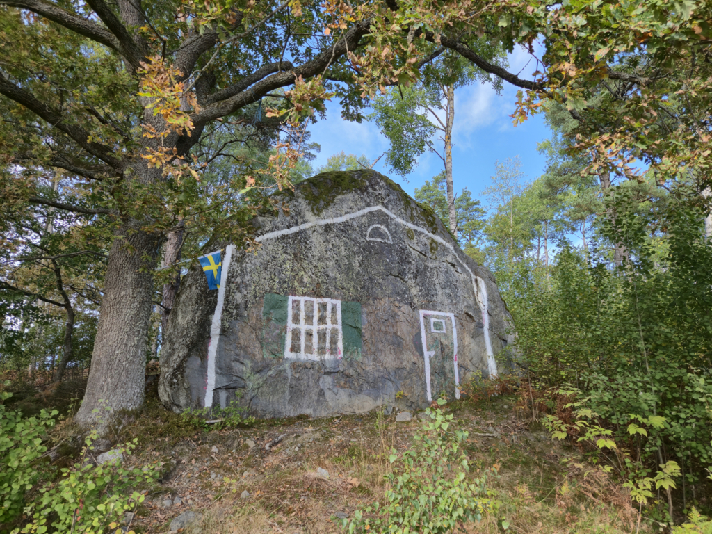 Konturerna av ett hus är målat på en jättestor sten.